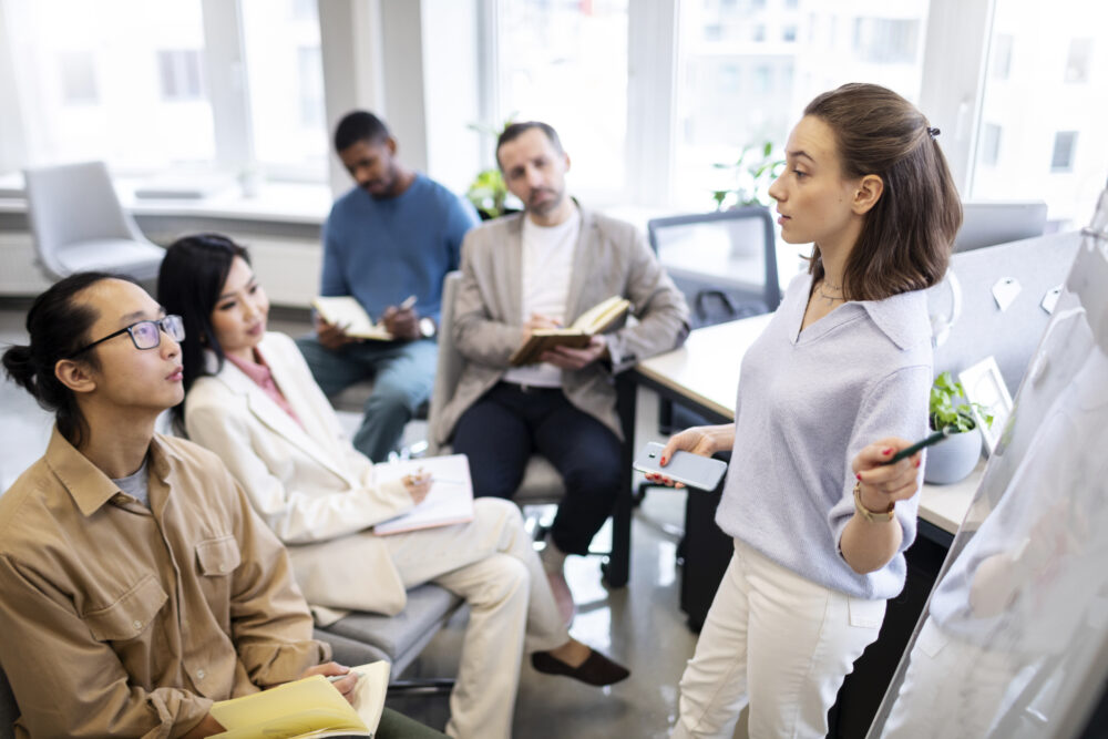 Group of people sitting and listening to women standing.