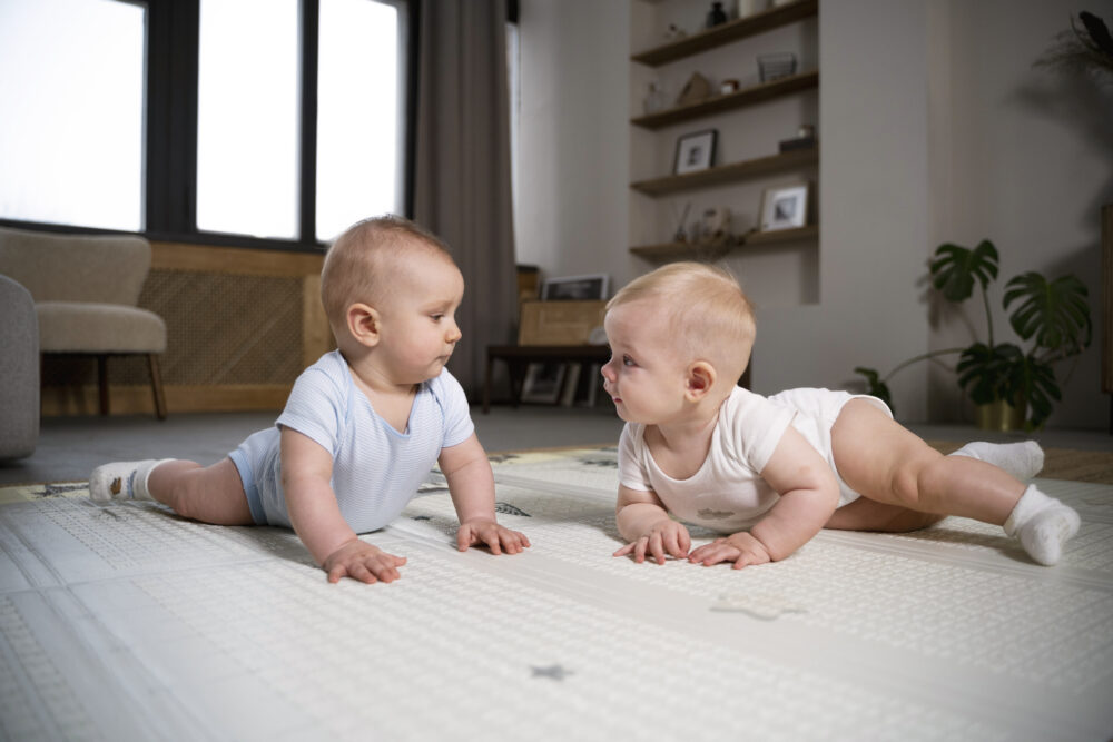 Two babies on a play mat facing each other