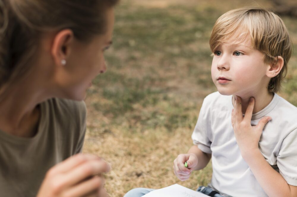 Adult talking to a child while the child touches their throat.
