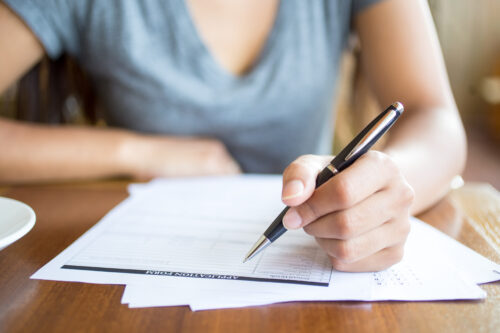 Women filling out form with a one in her hand.