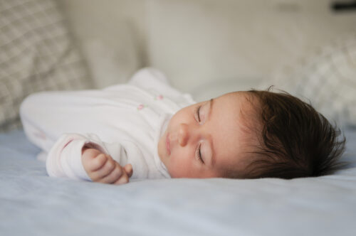 Sleeping baby lying on a bed.