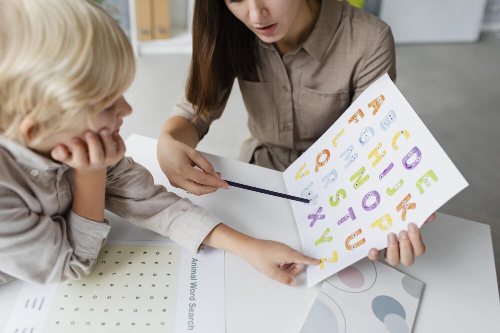 Adult pointing to alphabet letters while a child learns.
