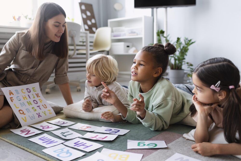 Adult showing alphabet cards to children sitting on the floor