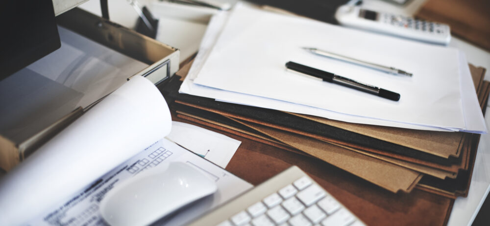 Office desk with paperwork, folders, and stationery.